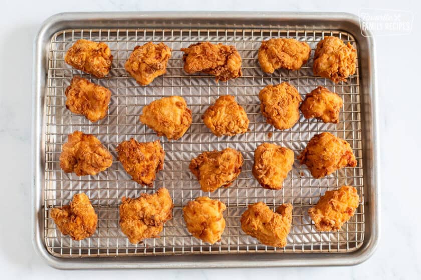 Cooling pieces of fried Mafa Chicken on a sheet pan.