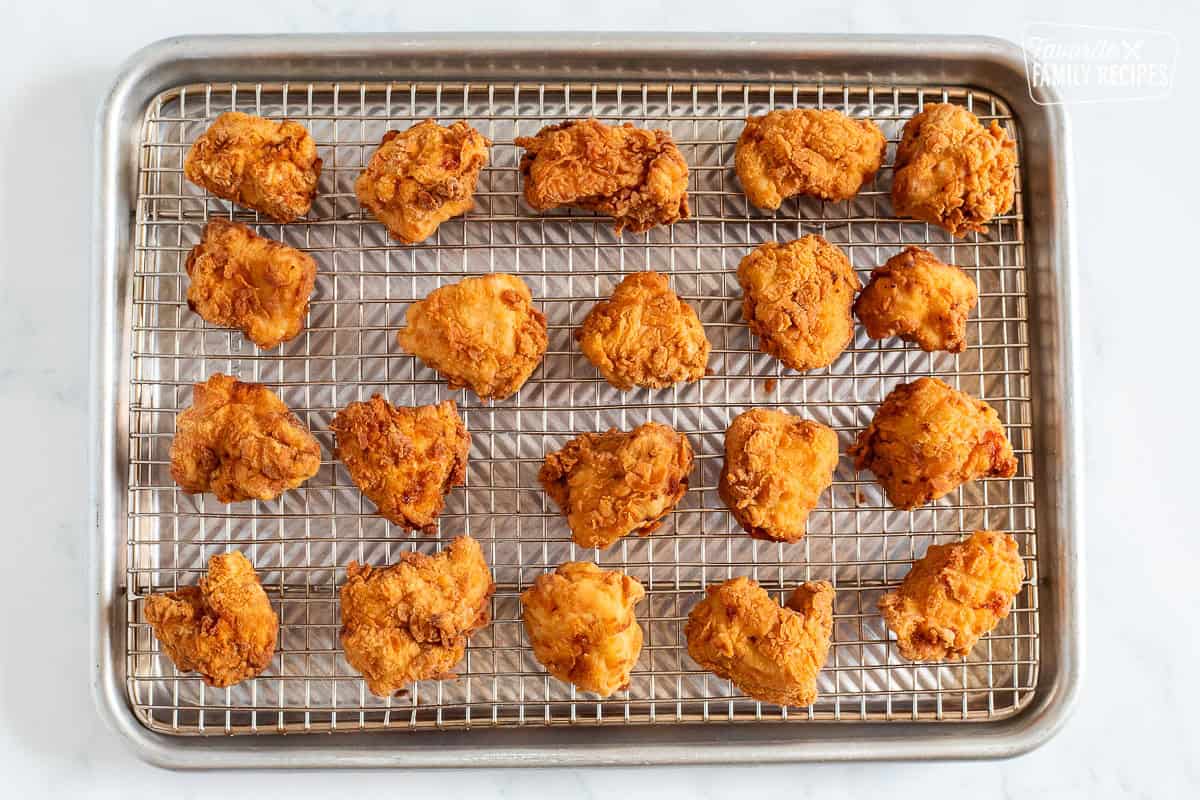 Cooling pieces of fried Mafa Chicken on a sheet pan.