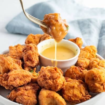 Dipping a piece of Mafa Chicken with a fork into sauce.