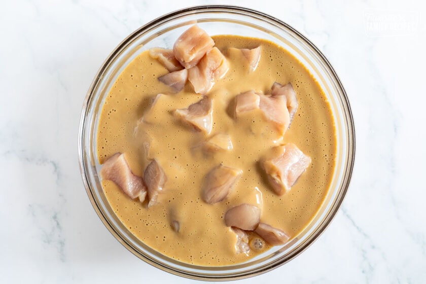 Glass bowl with chicken pieces marinading.