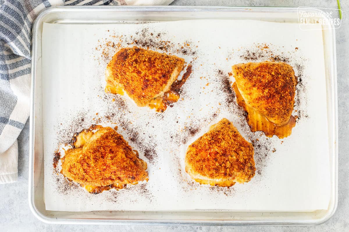 Baked parmesan chicken on a sheet pan with parchment paper.