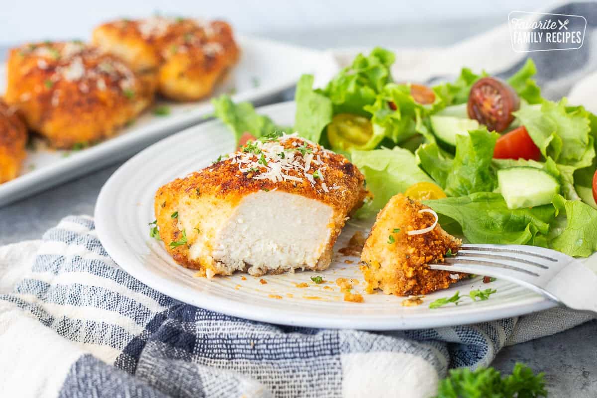 Parmesan chicken on a plate cut with side of salad.