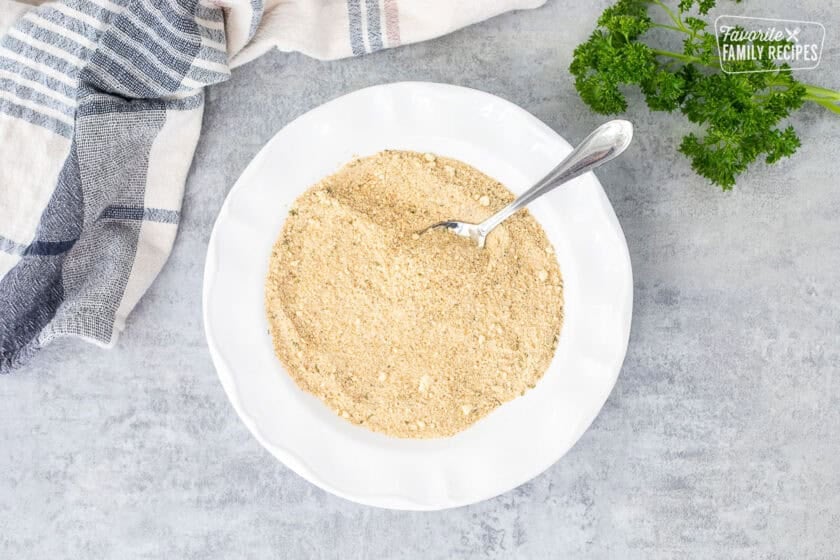 Bread crumb and parmesan cheese mixture in a bowl with a spoon.