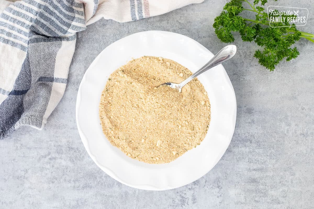 Bread crumb and parmesan cheese mixture in a bowl with a spoon.