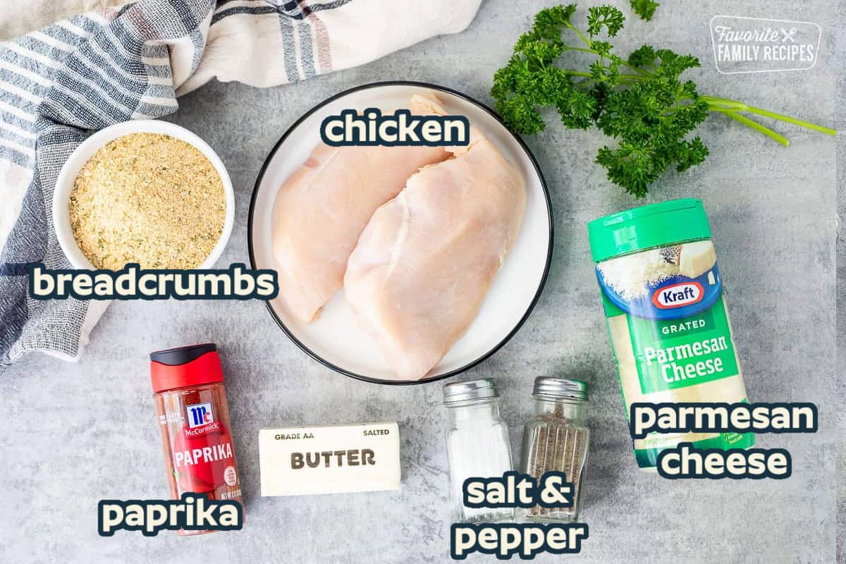 Ingredients to make parmesan chicken including chicken breasts, parmesan cheese, salt, pepper, butter, paprika and Italian seasoned bread crumbs.