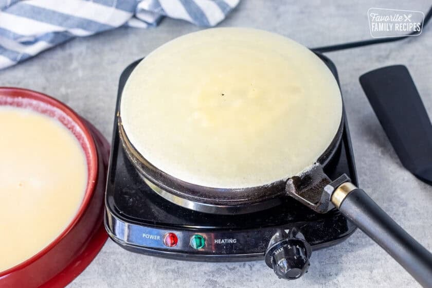 Crepe cooking on a crepe pan.