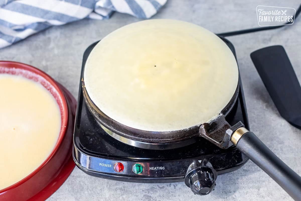 Crepe cooking on a crepe pan.