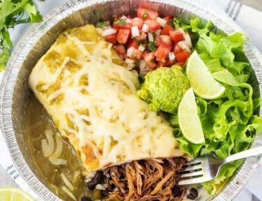 Inside sweet pork burrito with chopped lettuce, pico de Gallo, guacamole and lime wedges.