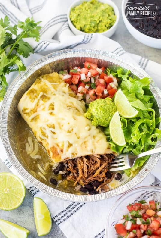 Inside sweet pork burrito with chopped lettuce, pico de Gallo, guacamole and lime wedges.