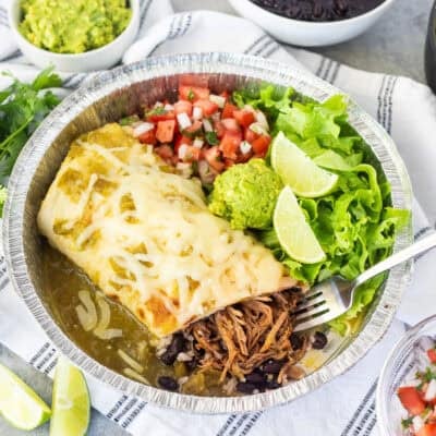 Inside sweet pork burrito with chopped lettuce, pico de Gallo, guacamole and lime wedges.