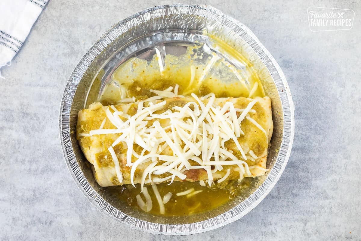 Dish with sweet pork burrito topped with green sauce and Monterey Jack cheese.