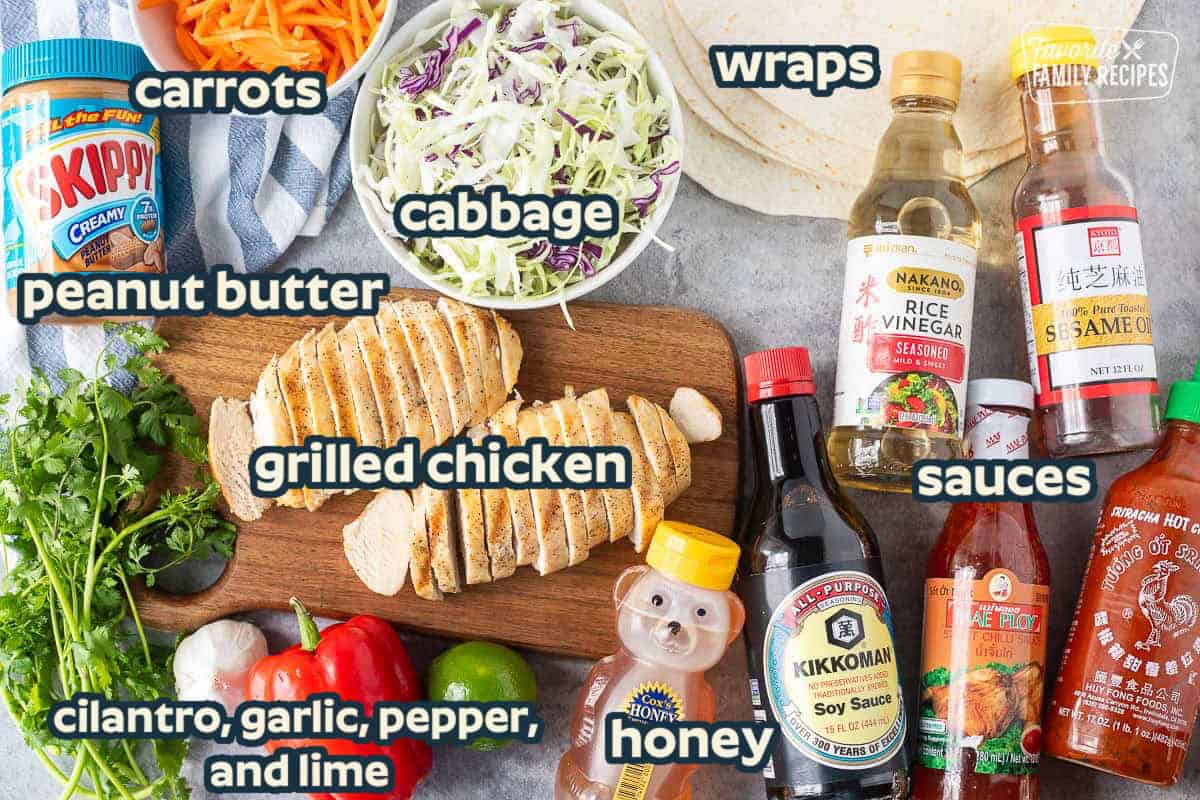 Ingredients to make Thai Chicken wraps including sesame oil, sriracha, rice vinegar, sweet chili sauce, soy sauce, honey, lime, red bell pepper, garlic, cilantro, peanut butter, carrots, cabbage and flour tortillas.