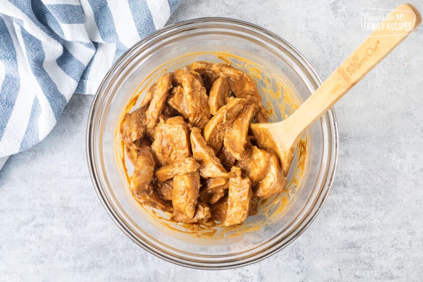 Chicken mixed with peanut sauce in a bowl.