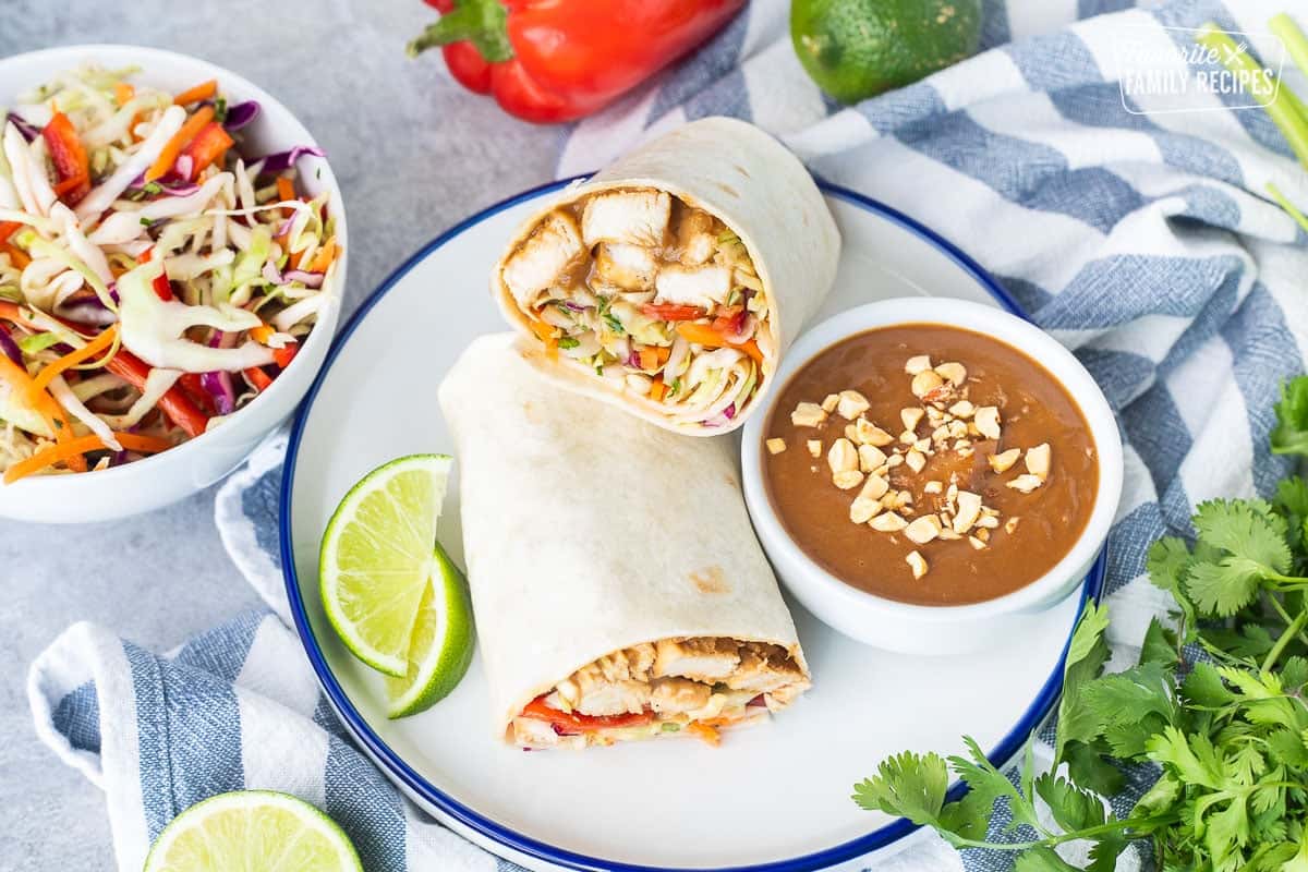 Thai Chicken Wrap halves on a plate with peanut sauce on the side.