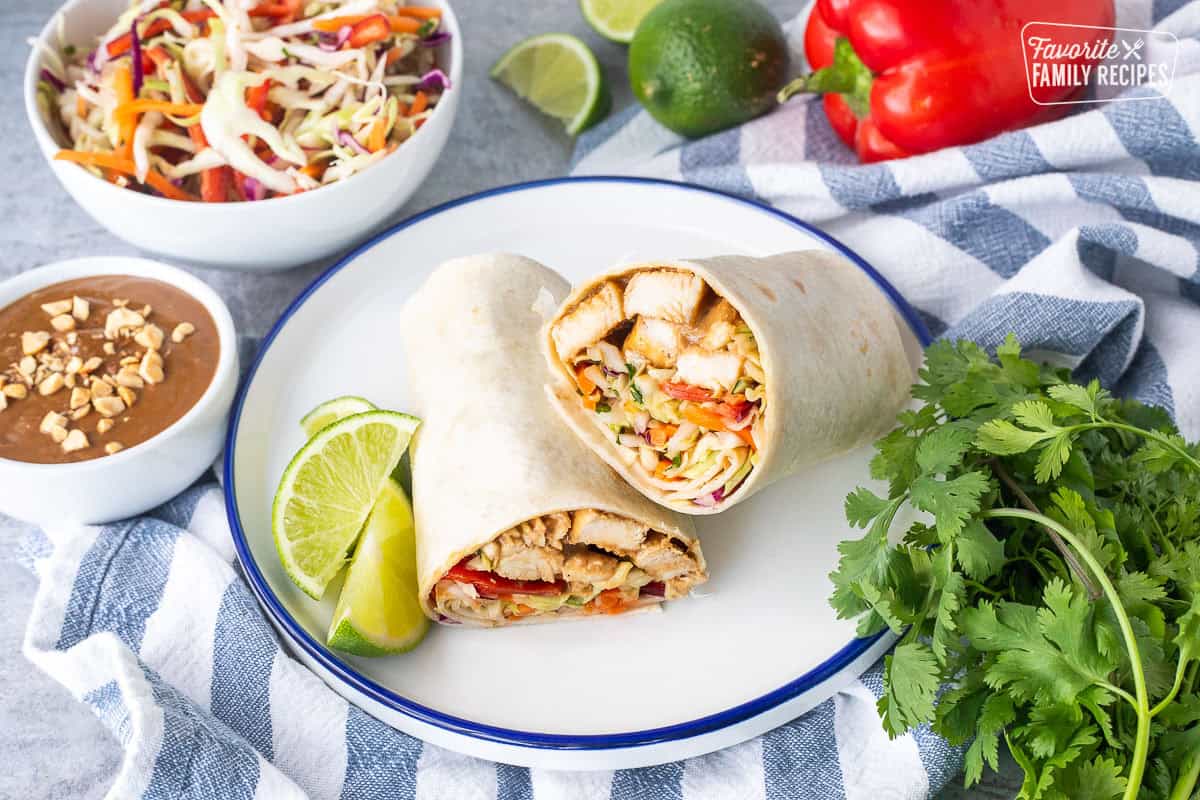Thai Chicken Wrap halves on a plate with peanut sauce on the side.