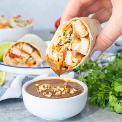 Dipping a Thai Chicken Wrap into a cup of peanut sauce.