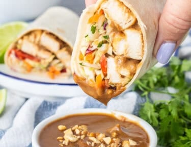 Dipping a Thai Chicken Wrap into a cup of peanut sauce.