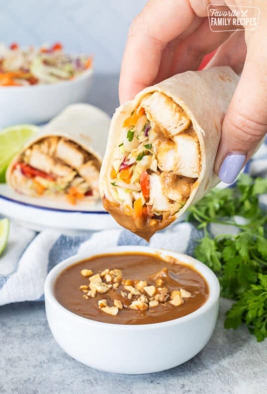 Dipping a Thai Chicken Wrap into a cup of peanut sauce.
