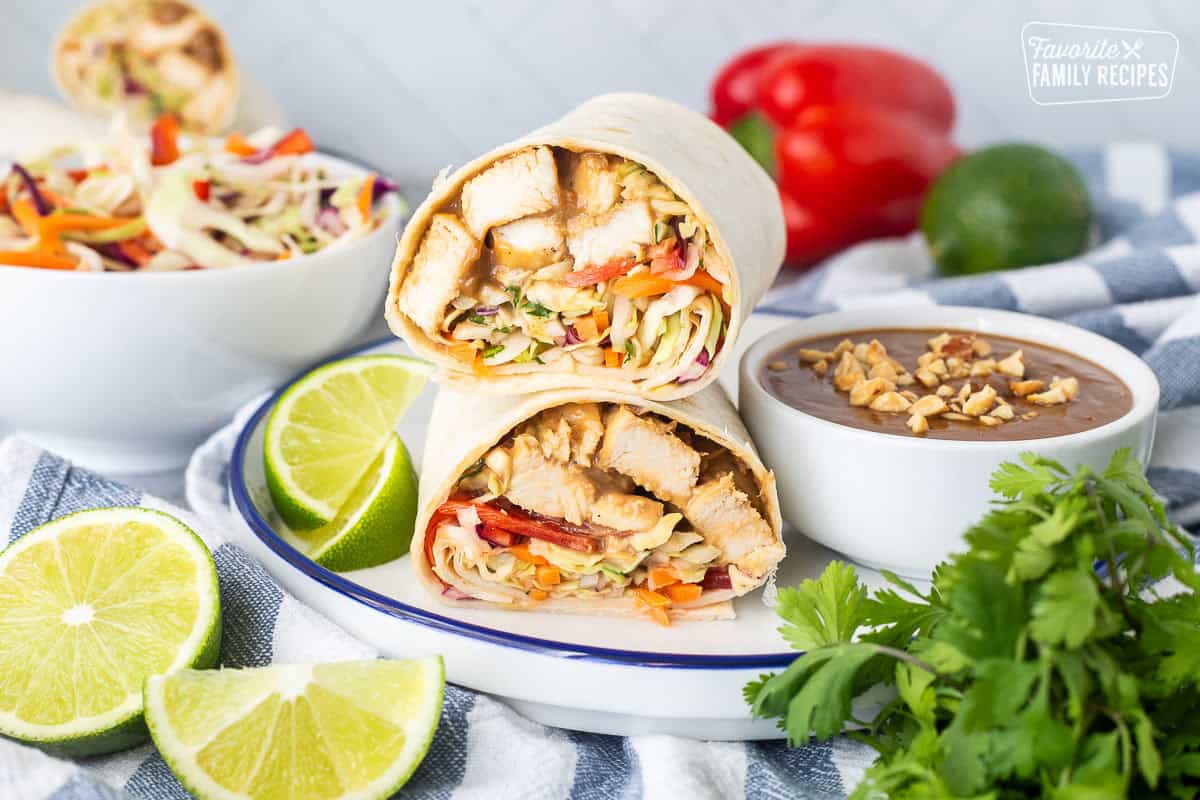 Thai Chicken Wrap halves stacked on top of each other and peanut sauce on the side.