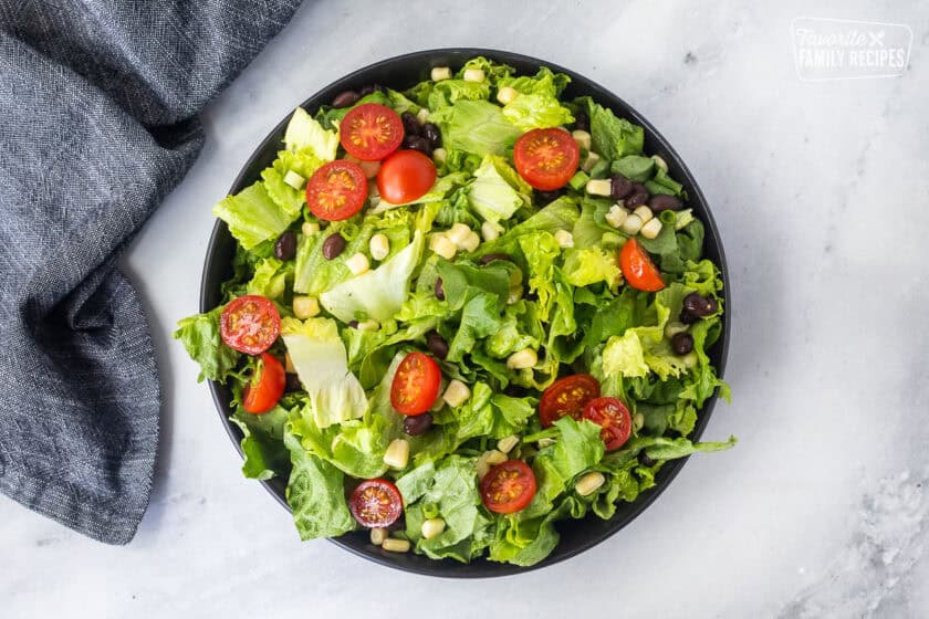 Bowl with lettuce, tomatoes, corn, and black beans.
