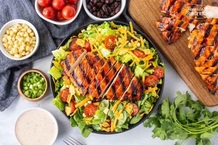 BBQ chicken salad with barbecue grilled chicken breast, lettuce, black beans, corn, tomatoes, crushed tortilla chips, green onion and shredded cheddar cheese. Creamy barbecue dressing on the side.