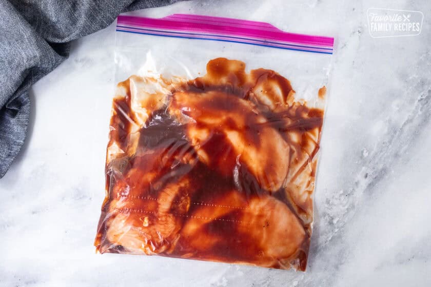 Bag with marinating chicken breasts with BBQ sauce.