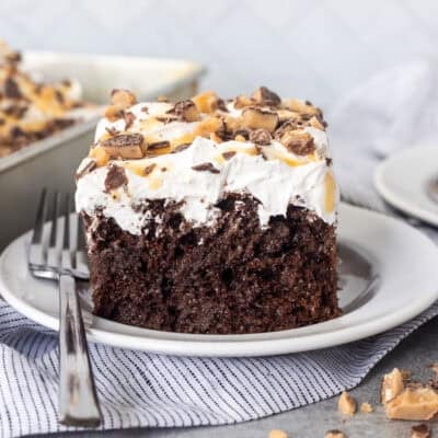 Better Than Sex Cake slice on a plate topped with Heath bars and caramel.