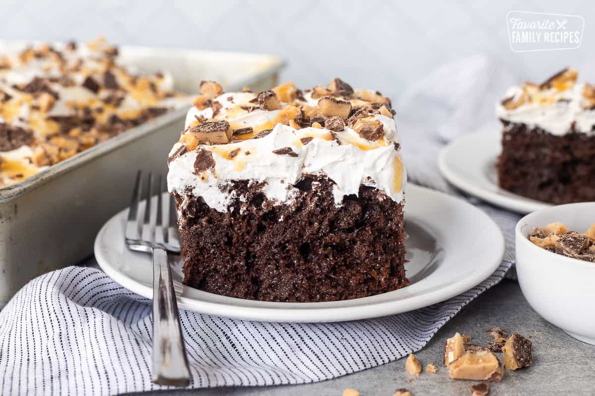 Better Than Sex Cake slice on a plate topped with Heath bars and caramel.