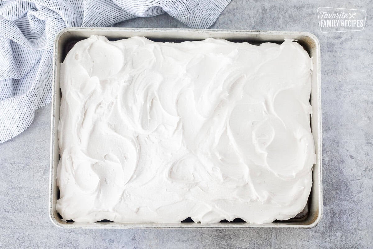 Cool whip on top of chocolate cake with caramel mixture.