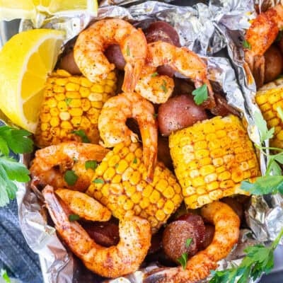 Cajun Foil Packet with shrimp, sausage, corn and red potatoes. Garnished with parsley and lemon wedges.