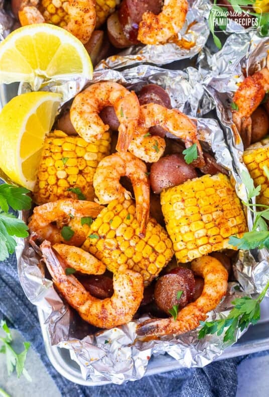 Cajun Foil Packet with shrimp, sausage, corn and red potatoes. Garnished with parsley and lemon wedges.