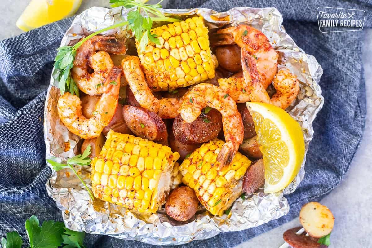 Cajun Foil Packet with shrimp, sausage, corn and red potatoes. Garnished with parsley and lemon wedges.