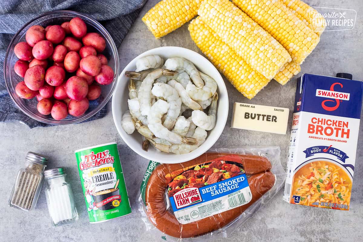 Ingredients to make Cajun Foil Packets including corn on the cob, chicken broth, butter, beef smoked sausage, creole seasoning, shrimp, small red potatoes, salt and pepper.