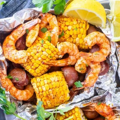 Cajun Foil Packet with shrimp, sausage, corn and red potatoes. Garnished with parsley and lemon wedges.
