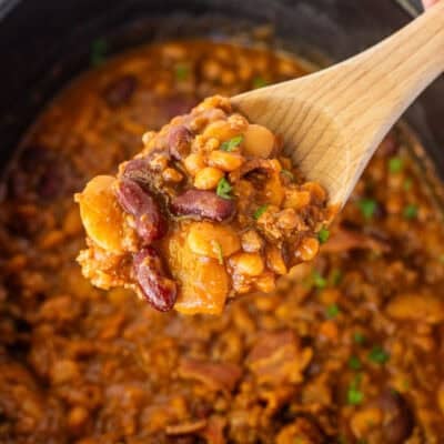 Wooden spoon full of calico beans over crockpot.