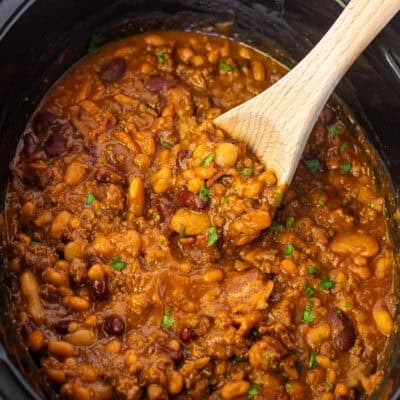 Crockpot with a wooden spoon full of calico beans.