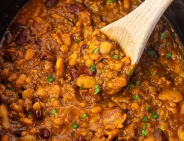 Crockpot with a wooden spoon full of calico beans.