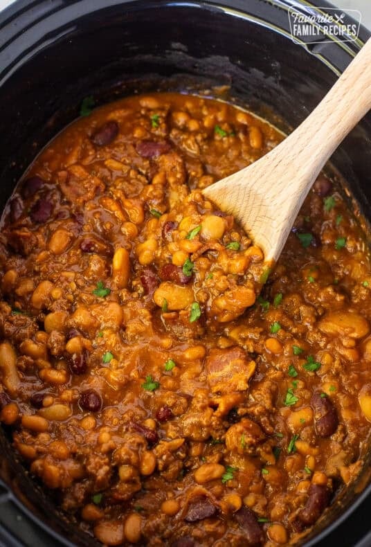Crockpot with a wooden spoon full of calico beans.