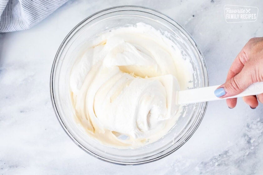 Folding cool whip into cream cheese mixture with a spatula.