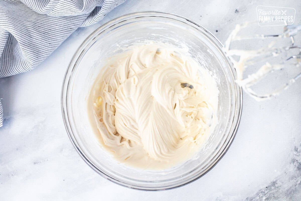 Cream cheese mixture whipped with beaters in a glass bowl.