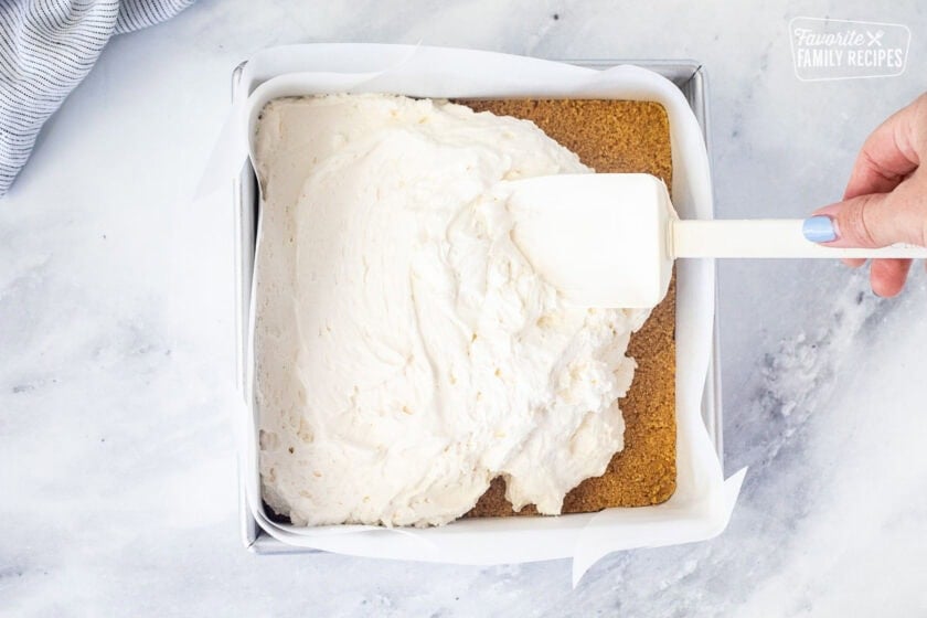 Smoothing cream cheese filling onto graham cracker crust.
