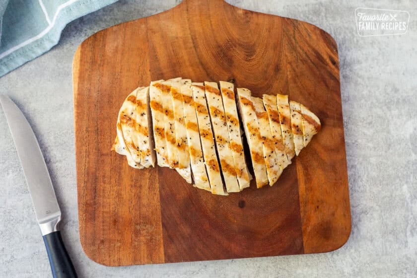 Cut grilled chicken breast on a cutting board.