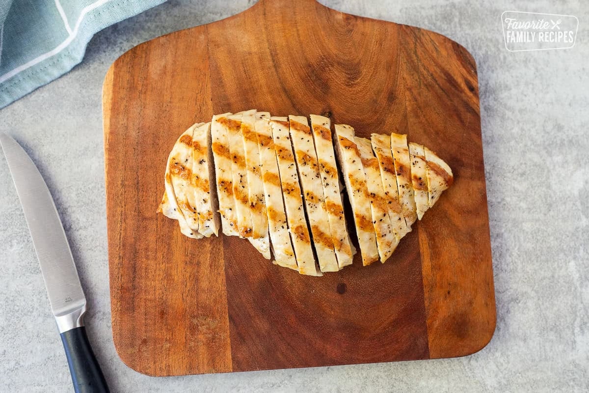 Cut grilled chicken breast on a cutting board.
