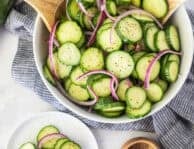 Plate of cucumber vinegar salad with sliced cucumbers and red onion.