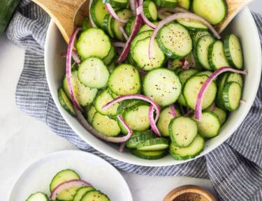 Plate of cucumber vinegar salad with sliced cucumbers and red onion.