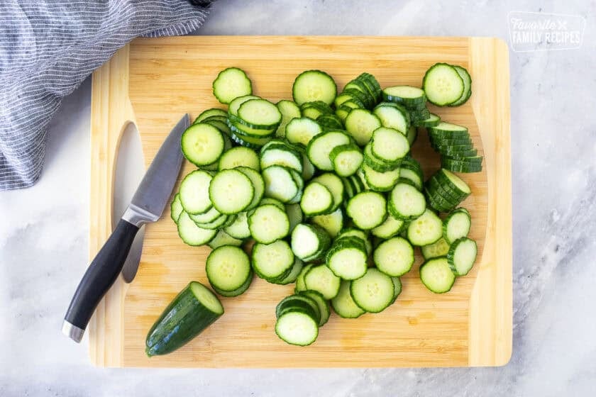 Sliced cucumber on a cutting board with a knife.