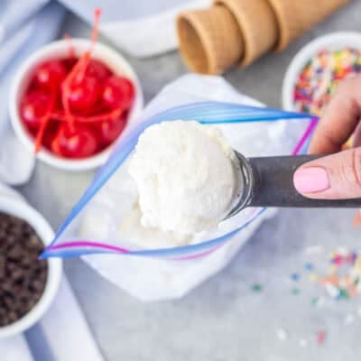 Scoop of homemade ice cream from a bag. Cones, sprinkles, cherries and chocolate chips on the side.