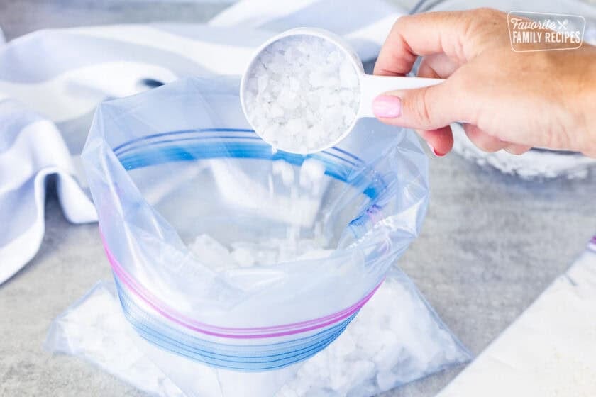 Pouring rock salt into large bag of crushed ice cubes.