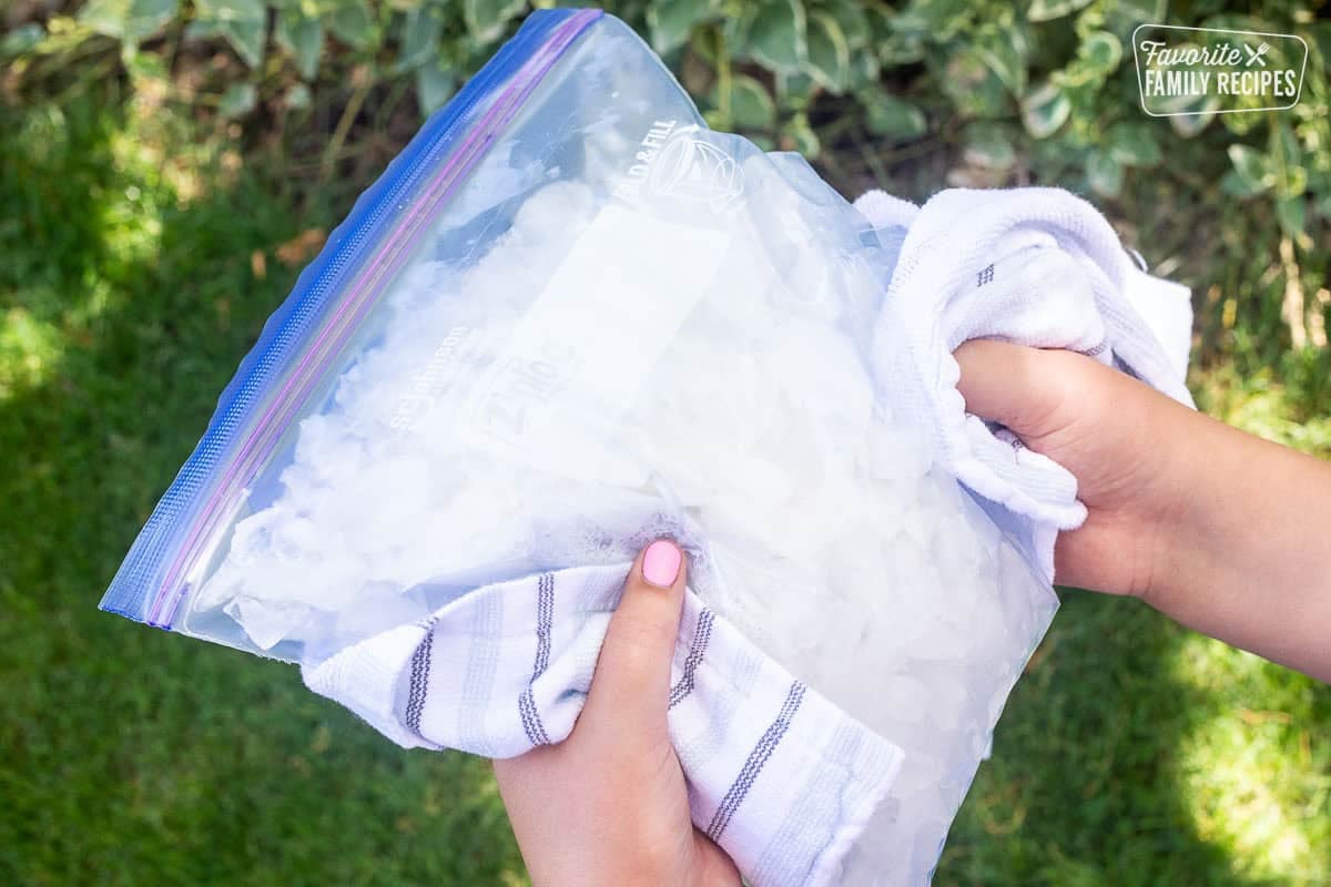Shaking ice cream in a bag by hand with towel wrapped around bag.