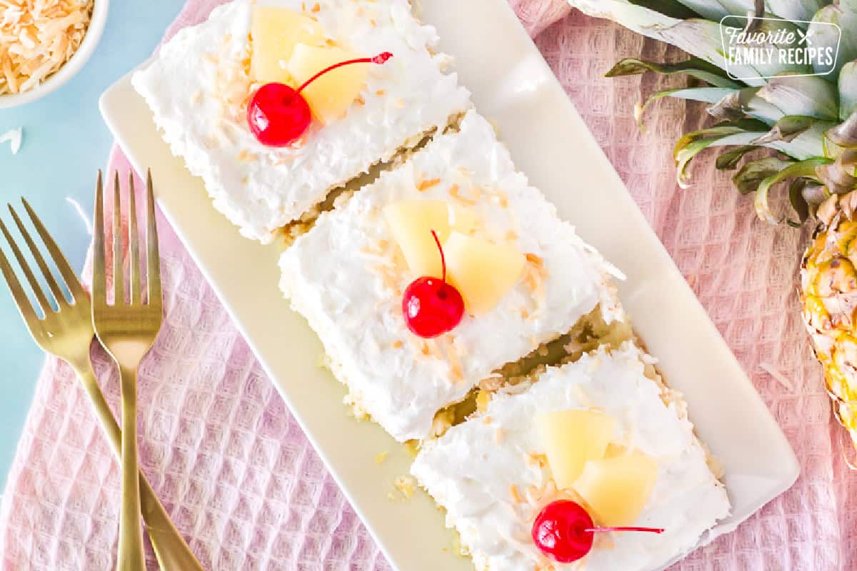 Top view of three slices of Pina Colada Cake. Garnished with cherries, sliced pineapple and toasted coconut.